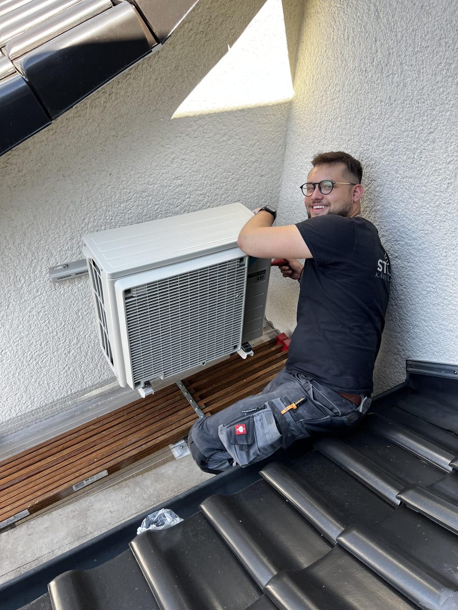 Rokas Stiller, Kälteanlagenbaumeister, montiert ein Außengerät auf dem Dach